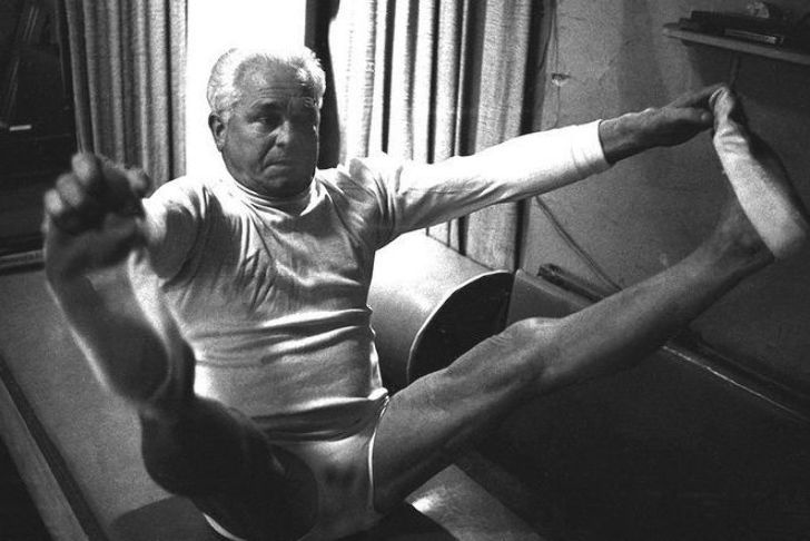 Exercício clássico do método Pilates num aparelho de madeira