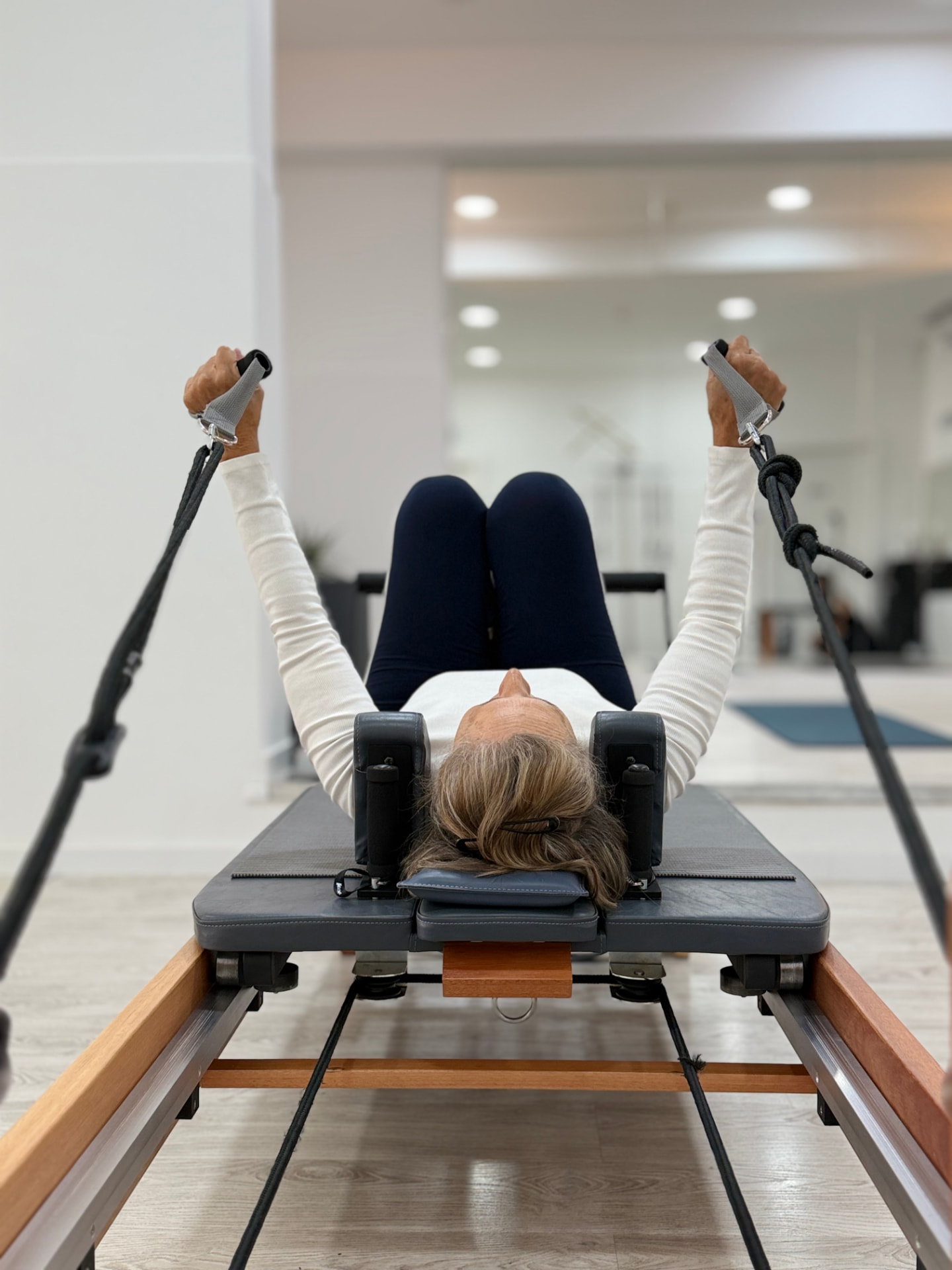 Aluna no reformer em exercício de braços com molas